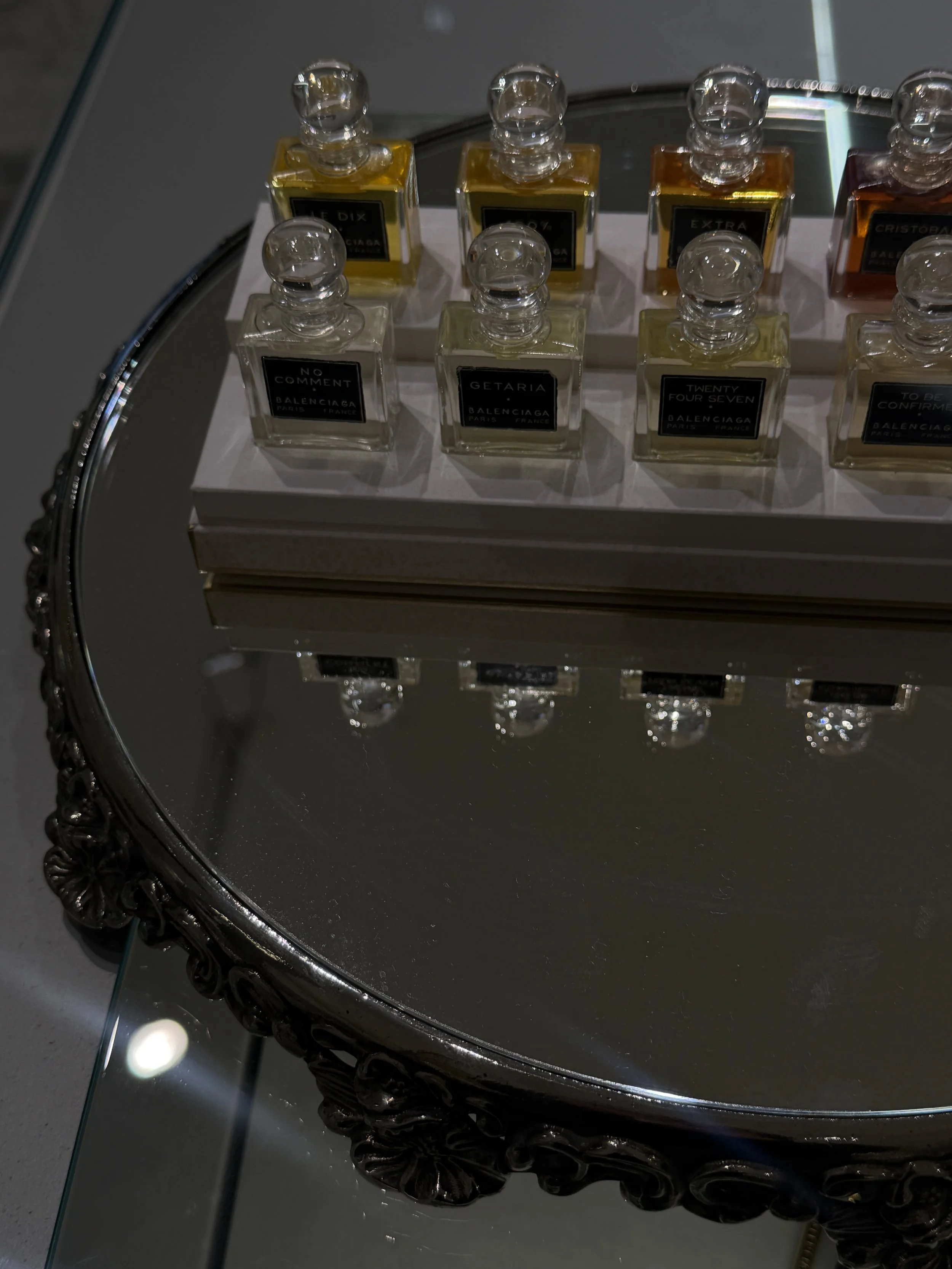 Display of several bottles of perfume on a mirrored tray.