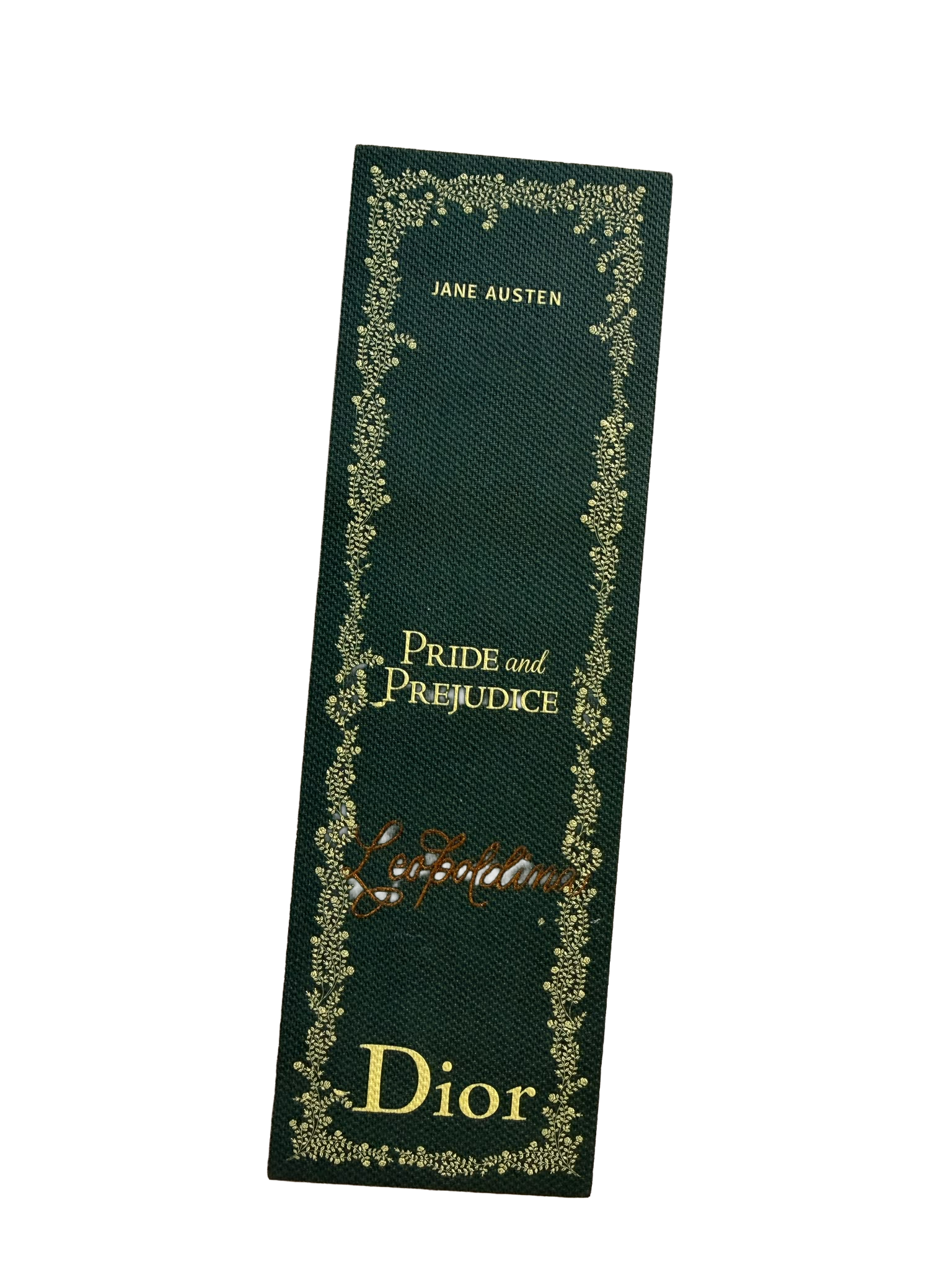 Close-up of a black fabric bookmark with gold floral border and text reading 'Jane Austen Pride and Prejudice D'.