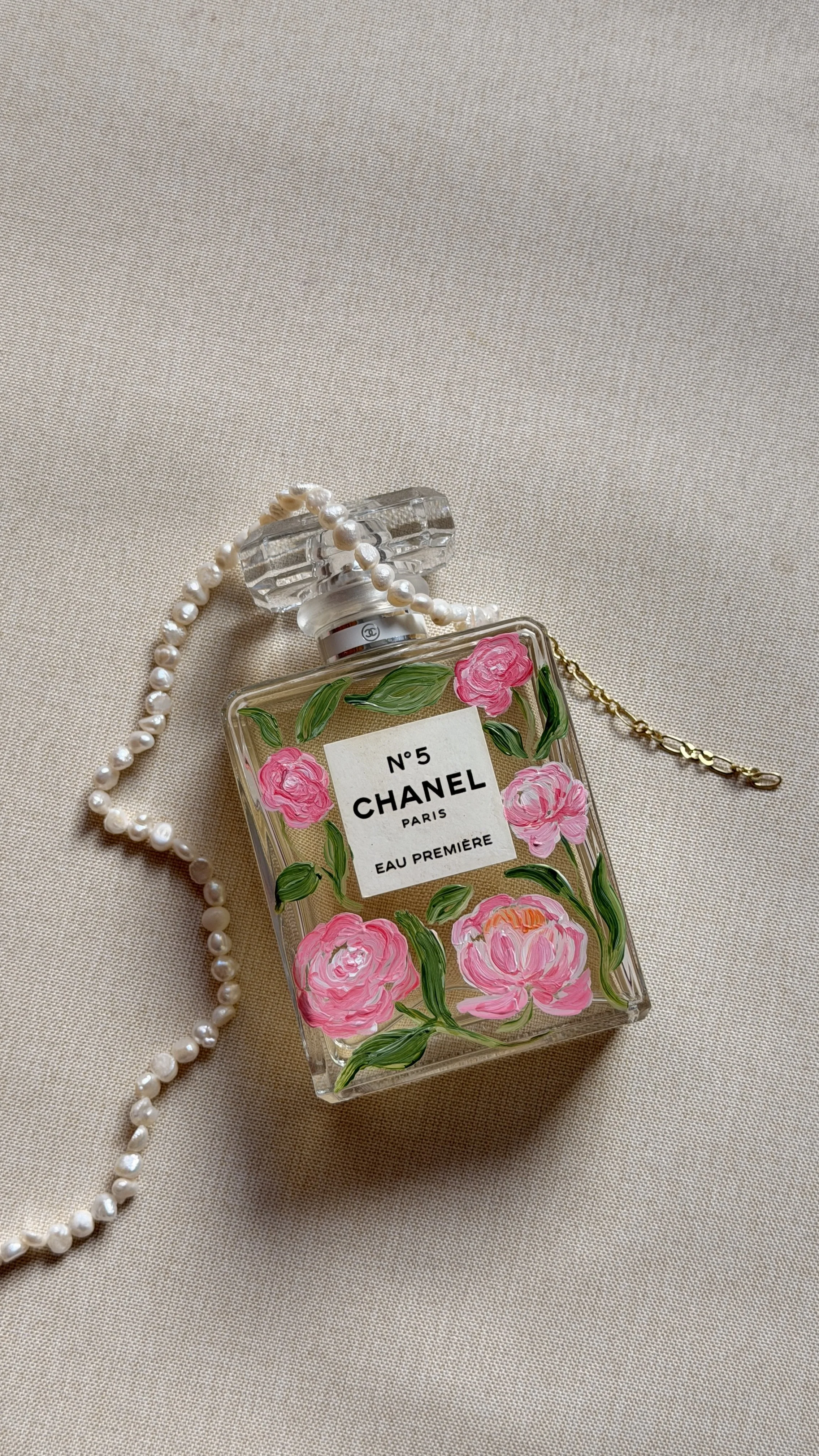A Chanel No. 5 perfume bottle decorated with pink and green floral painting