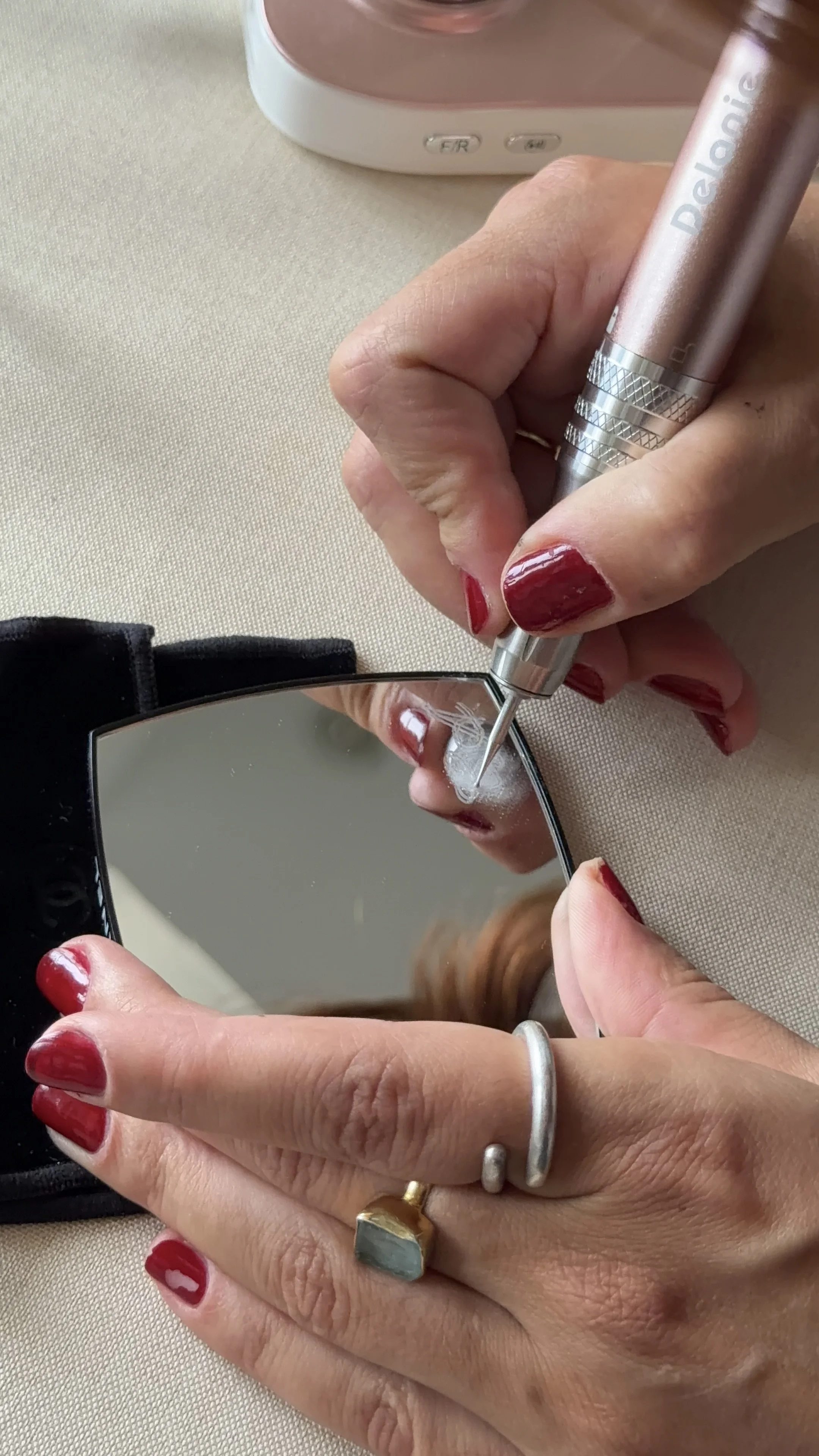 Close-up of hands using an engraving tool to personalise Chanel beauty pocket mirror