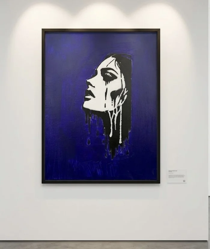 Street art-style painting of a woman's face with black and white contrast and blue background, appearing to have paint dripping down.
