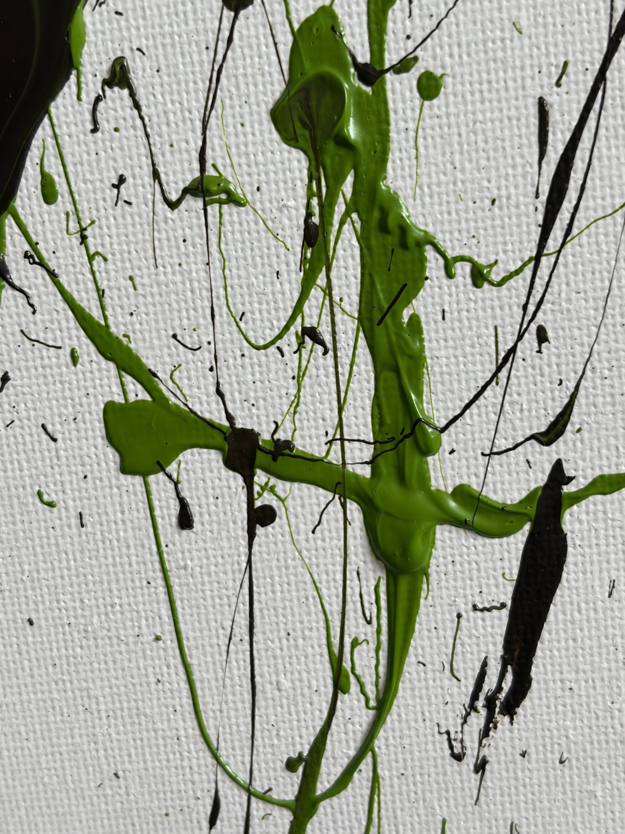 Abstract painting with black and green paint splattered on a white textured canvas.