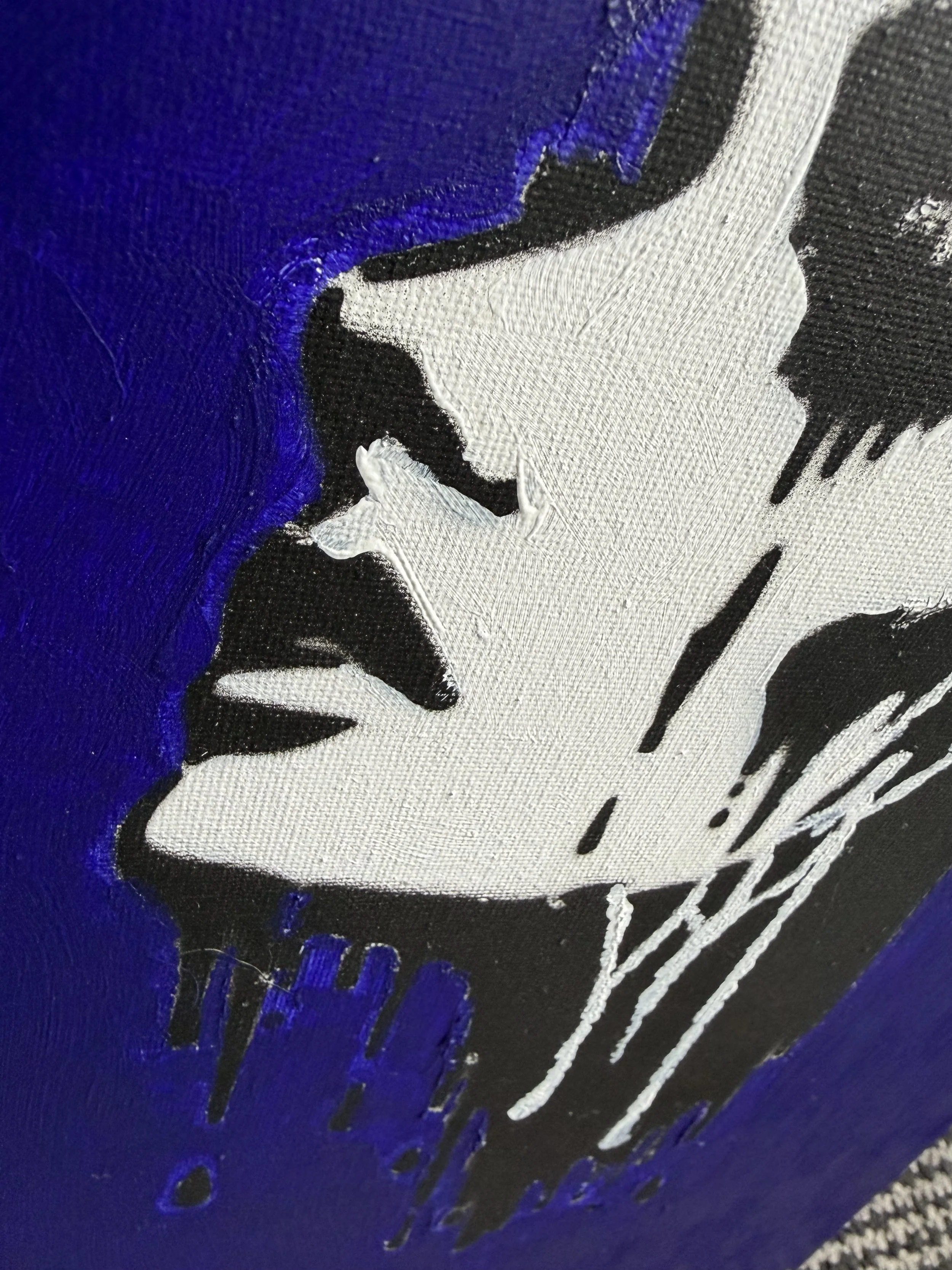 Close-up of a graffiti-style artwork featuring white, black, and purple paint on a textured surface.