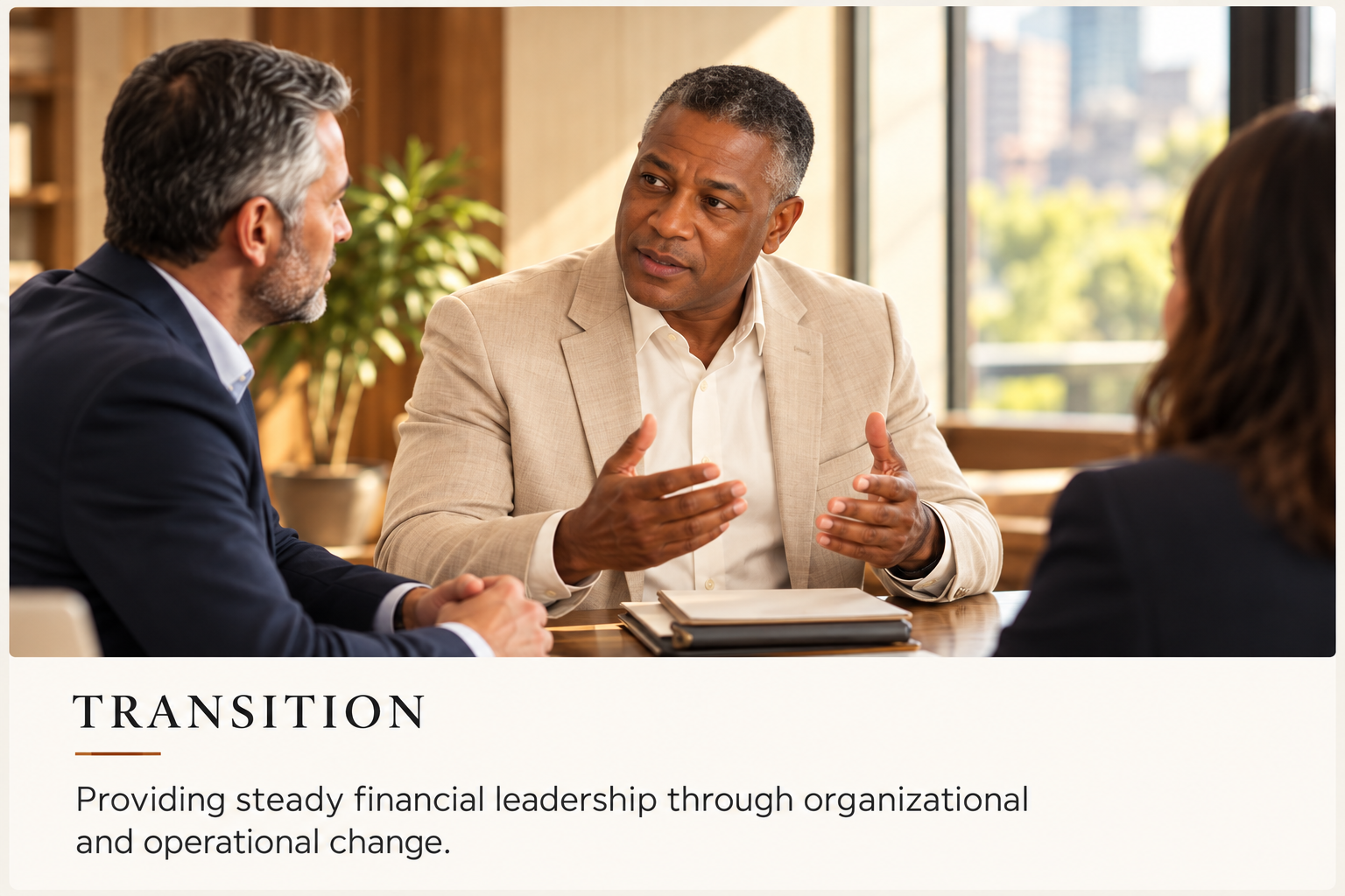 Three business professionals engaged in a discussion in a bright office setting, with one man in a beige suit actively talking and gesturing while the other two listen attentively.
