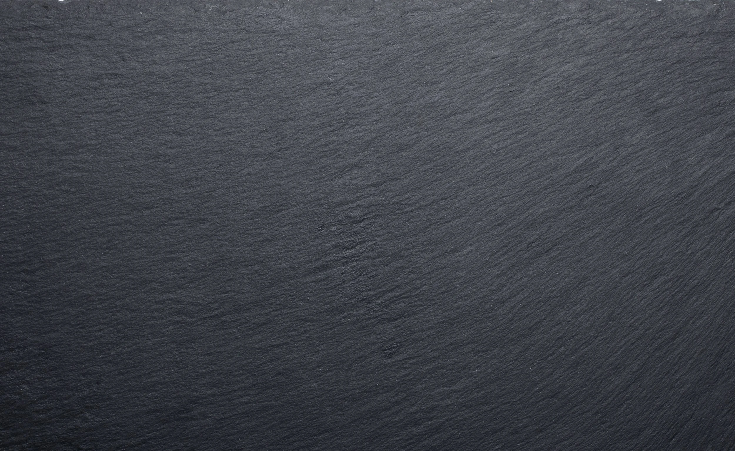 Close-up of a dark gray slate or stone surface with textured, rough appearance.