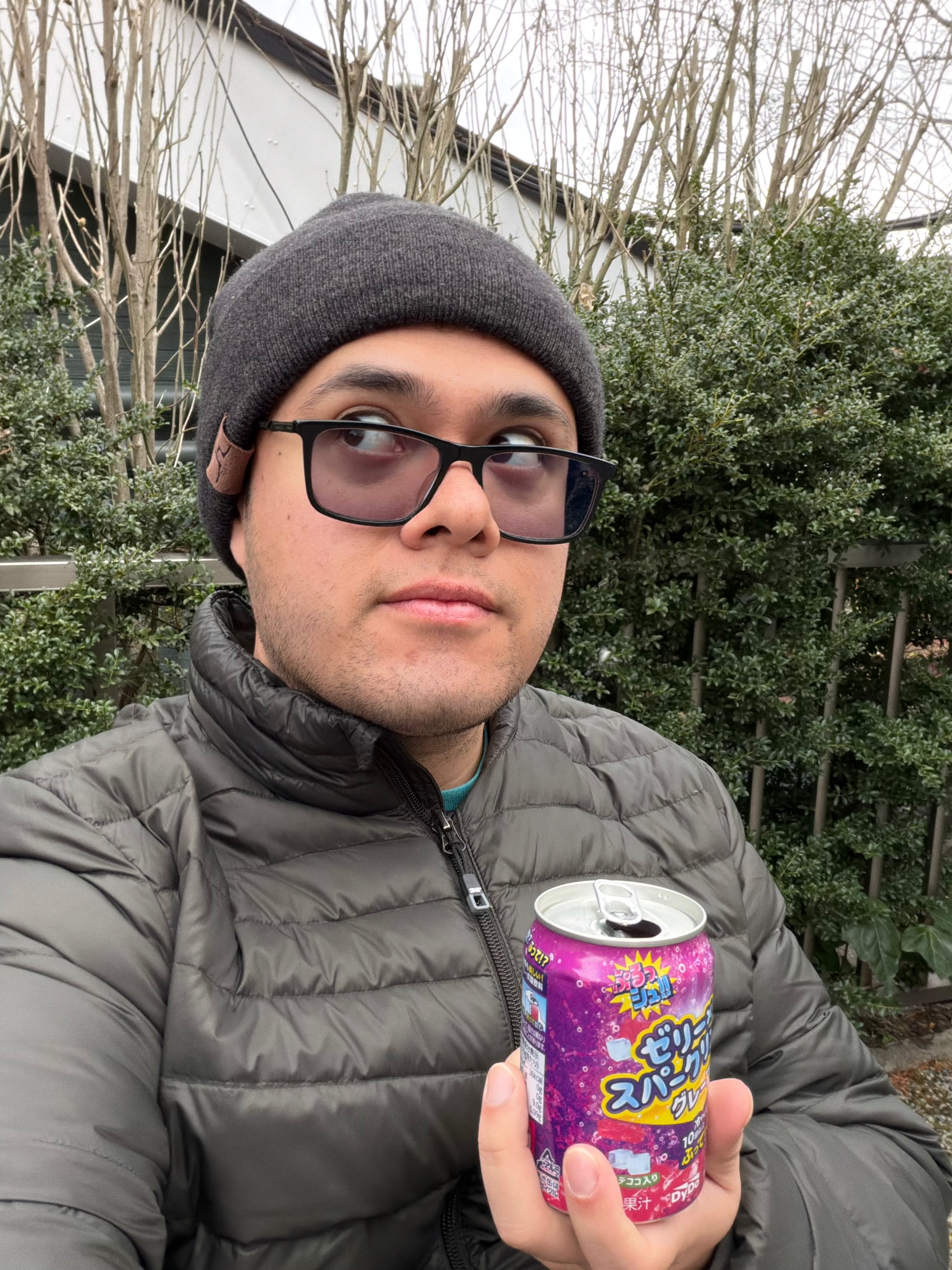 Portrait of Juan outdoors holding a can of Japanese soda.