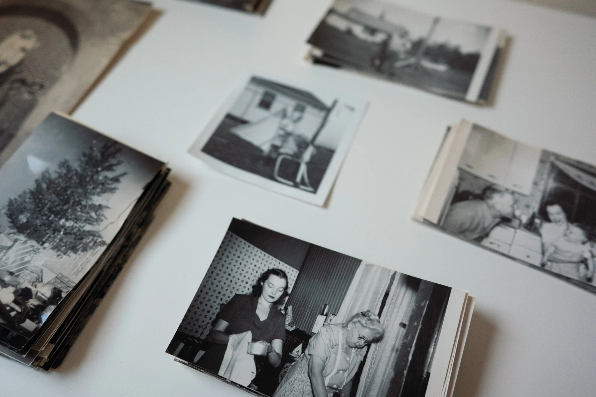 A collection of black and white photographs displayed on a white surface, featuring various scenes including people, buildings, and outdoor landscapes.
