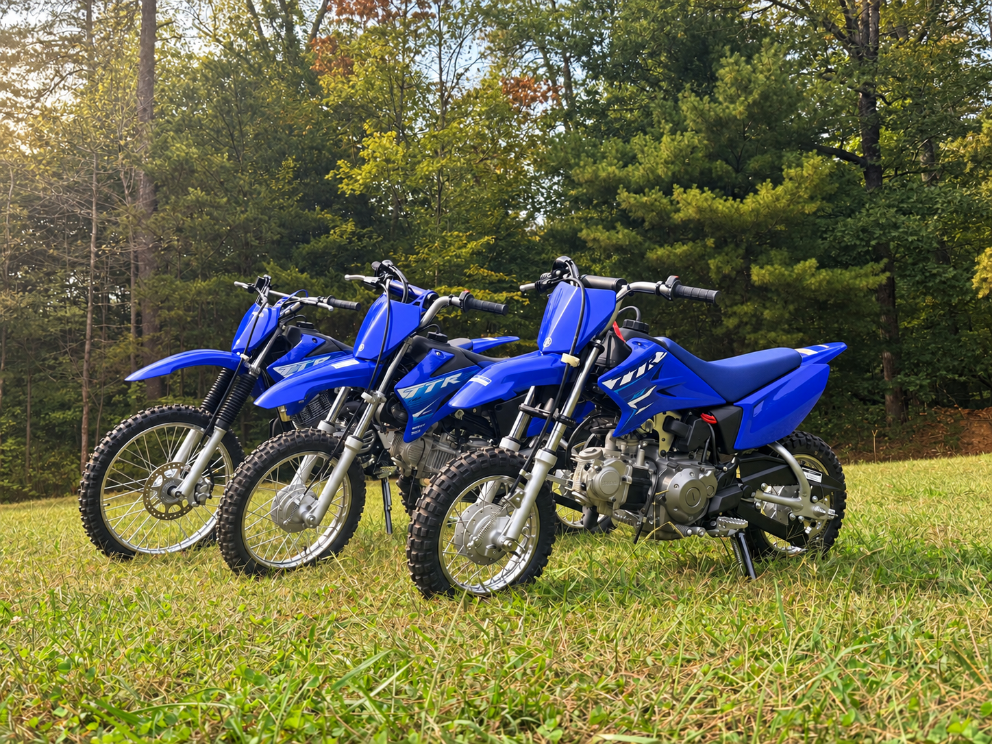 Youth-sized dirt bikes parked on grass, available for kids' dirt bike rentals through Waymaker Off-Road at Brushy Mountain Motor Sports Park in Taylorsville, NC.