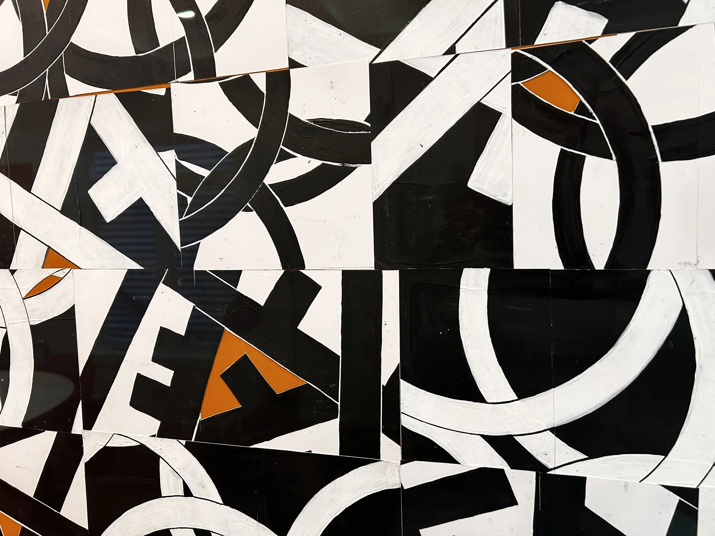 Abstract black, white, and orange geometric mural with curved and straight lines.