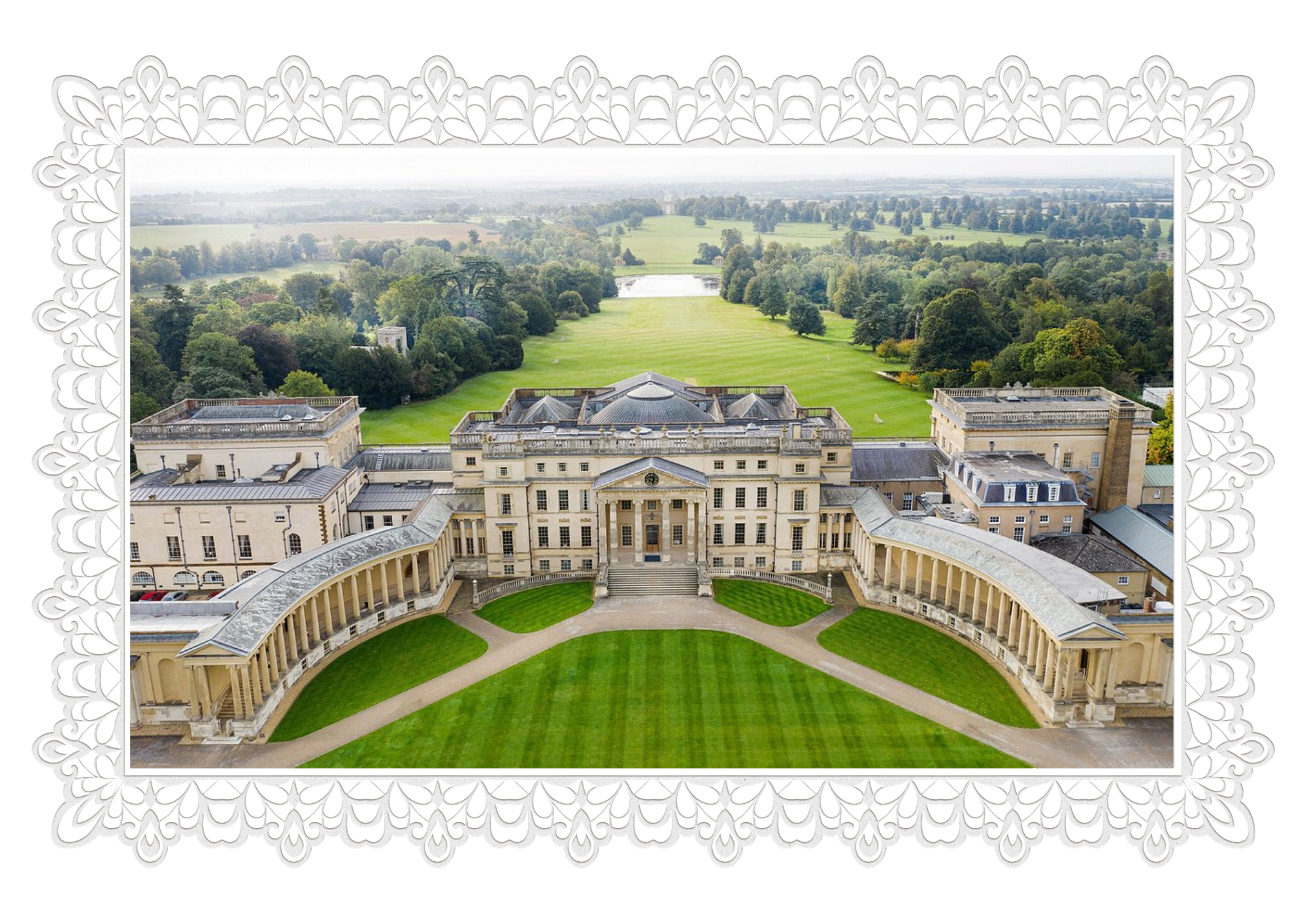 A grand historic building with a central domed roof, surrounded by a curved colonnade and lush green lawns, overlooking expansive parks and countryside.