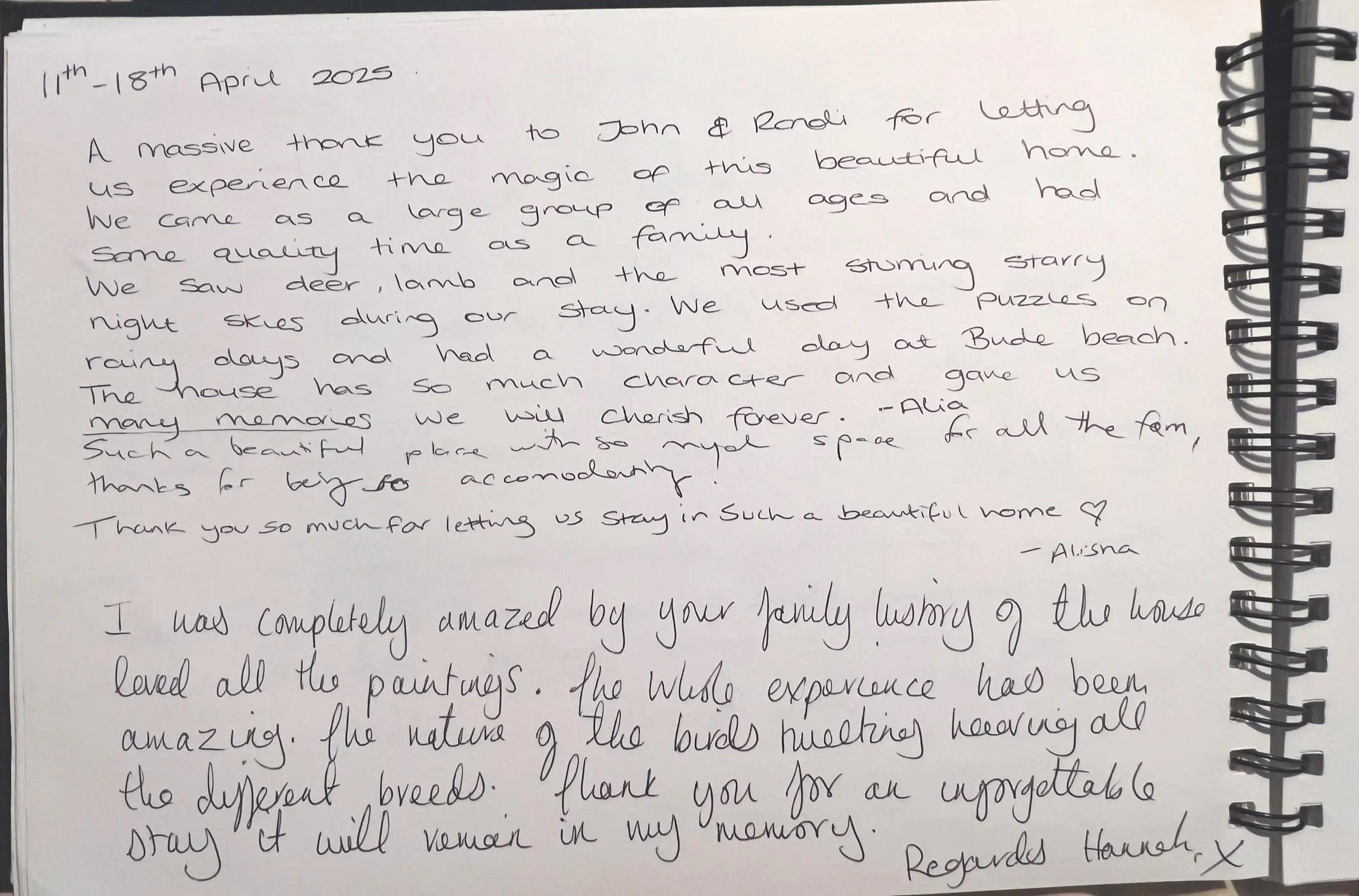 A handwritten thank you note on a spiral-bound notepad, dated April 11th-18th, 2025. The note expresses gratitude to John and Randi for allowing the writers to experience their home, mentioning activities like seeing deer and lambs, enjoying puzzles, and having a wonderful day at Bude beach. The note is signed by Alisha and mentions the beautiful home and the family history of the house.