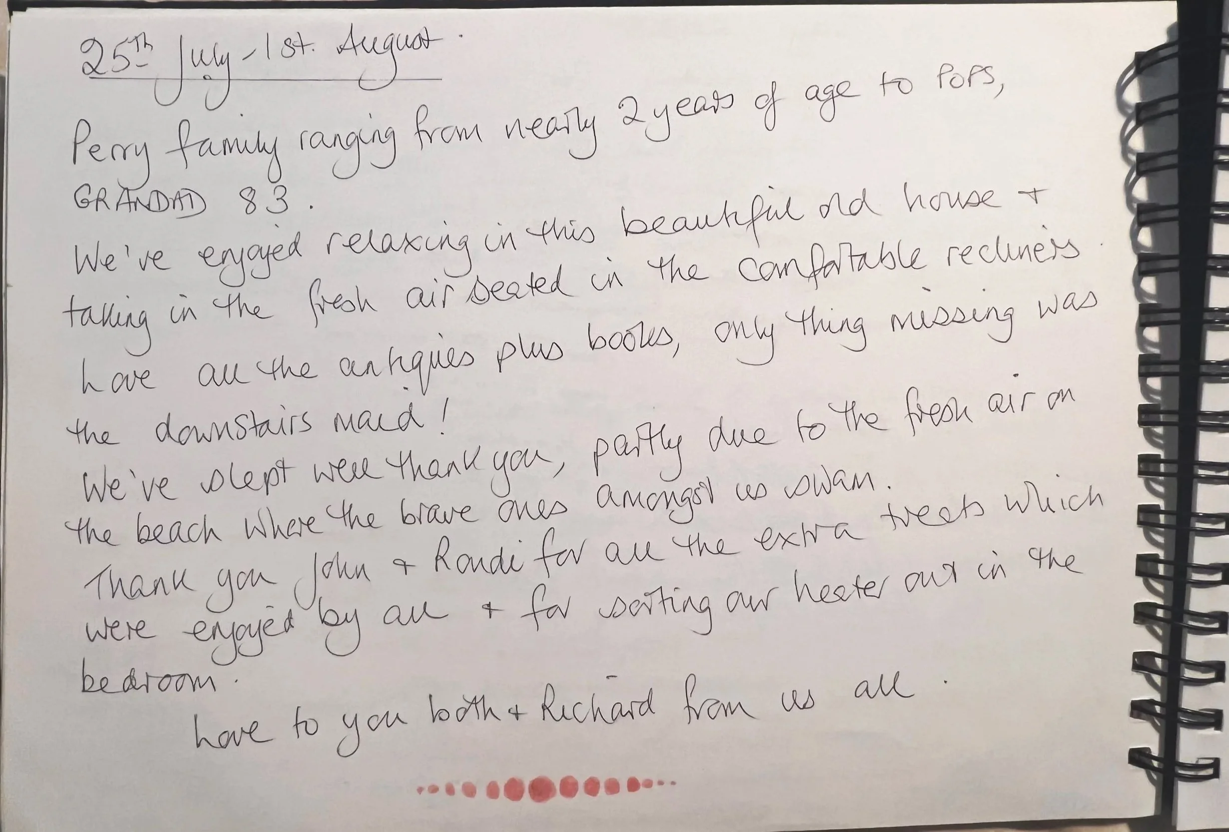 Handwritten letter on a white paper, with a black spiral notebook binding on the right side. The letter appears to be a personal note, mentioning a family visit, enjoying relaxing in a house, and some thank yous. There is a red lipstick kiss mark at the bottom of the letter.