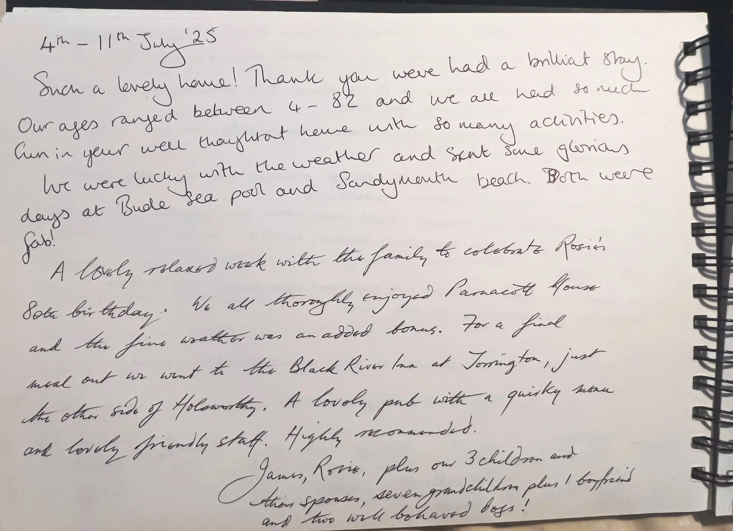 A handwritten letter on a spiral-bound notepad with cursive script, dated July 25, discussing a visit, weather, and activities at beaches and locations in Bude.