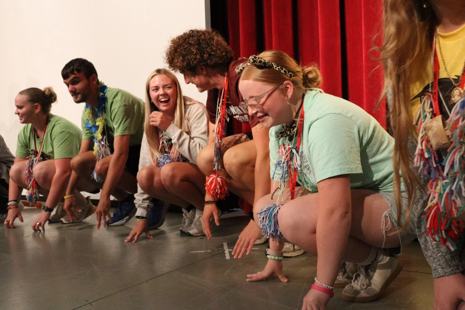Group of young adults crouching and laughing during a colorful stage performance