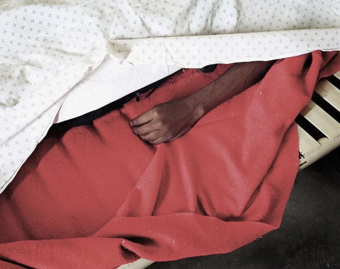 The hand aof a recently deceased man on a red blanket in a mortuary in Cape Town, South Africa.