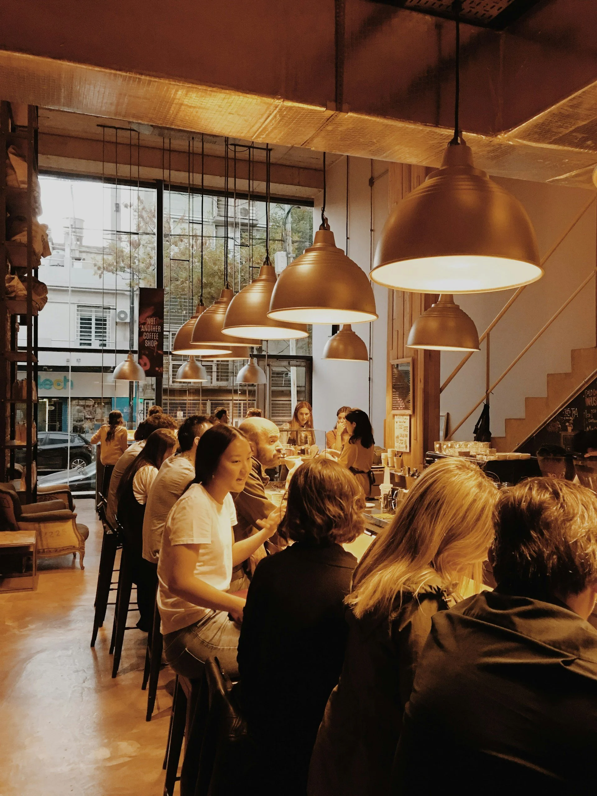 Busy neighborhood restaurant with pendant lights and guests seated at the bar