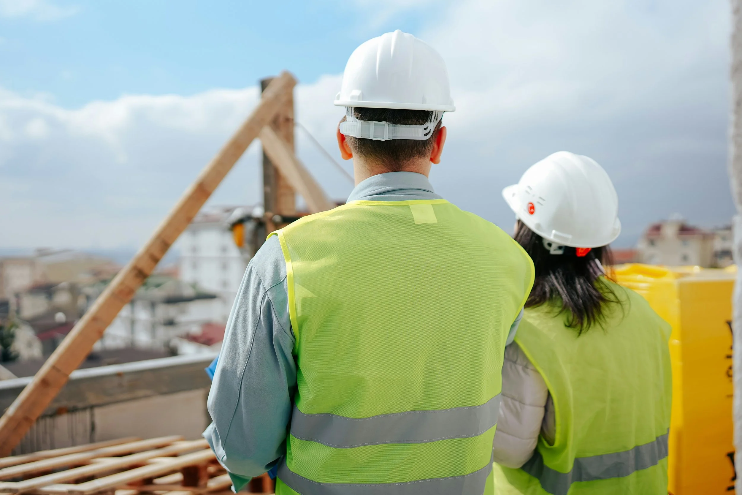 Construction managers in hard hats and safety vests overseeing a commercial development site