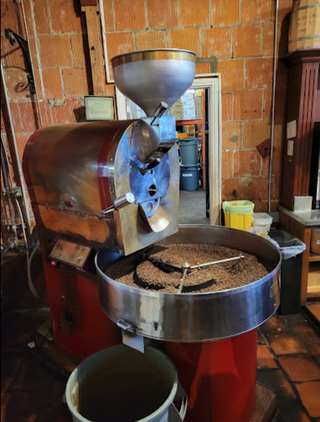Coffee roasting machine with cooling tray and roasted coffee beans in a brick-walled workshop