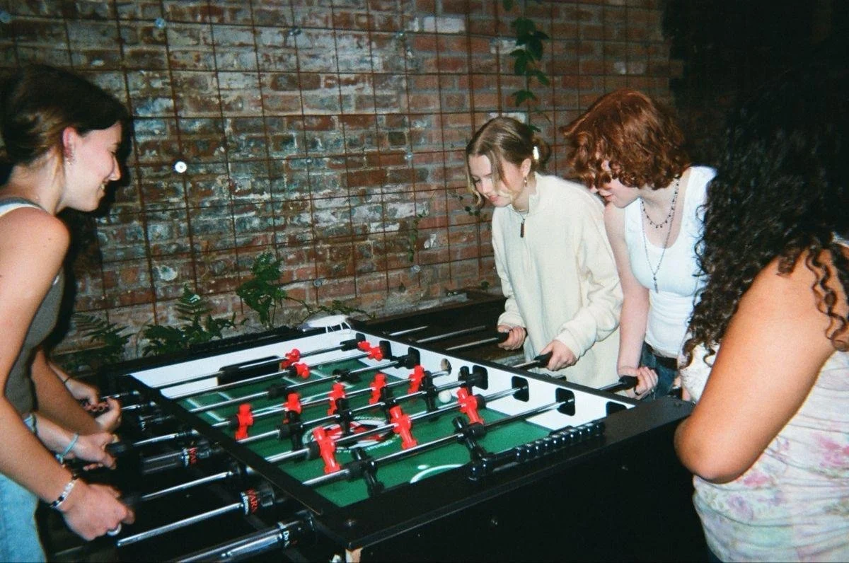 Friends gathered around a foosball table.