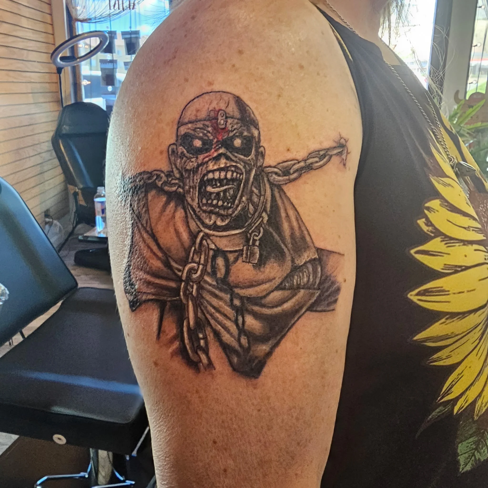 Tattoo of a skeleton with chains on upper arm.