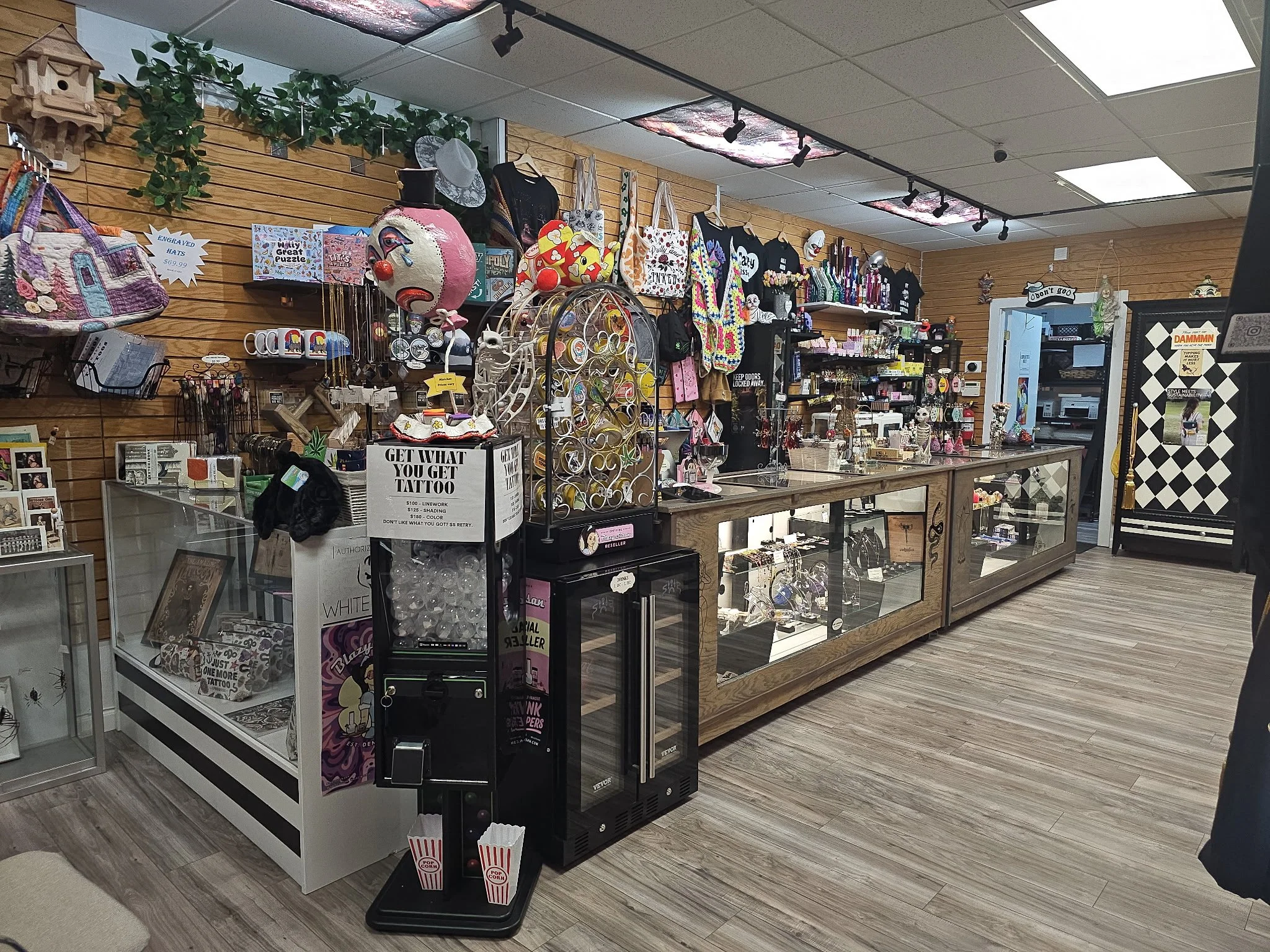 Interior of a gift shop with merchandise on wooden walls, including bags, hats, jewelry, and decorative items, and a glass display case containing smaller items.