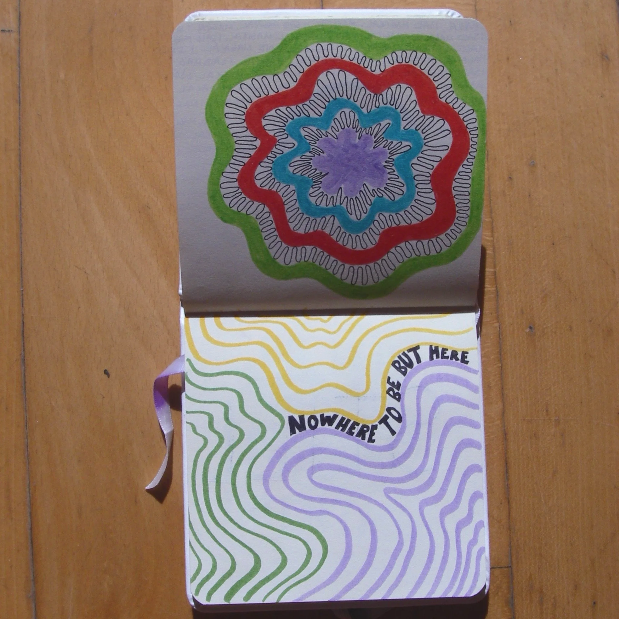 Colorful coaster featuring concentric wavy lines in purple, green, yellow, blue, red, and white, creating a flower-like pattern, on a wooden surface.