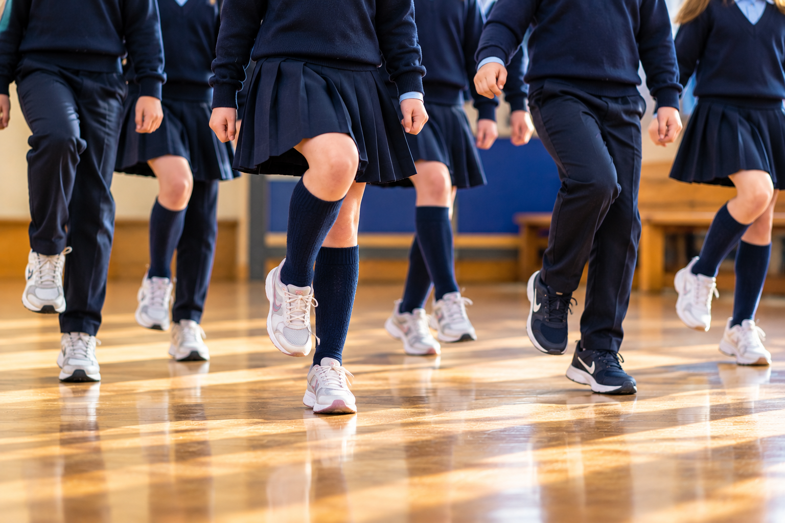 Students in school uniforms jumping in a gym class.