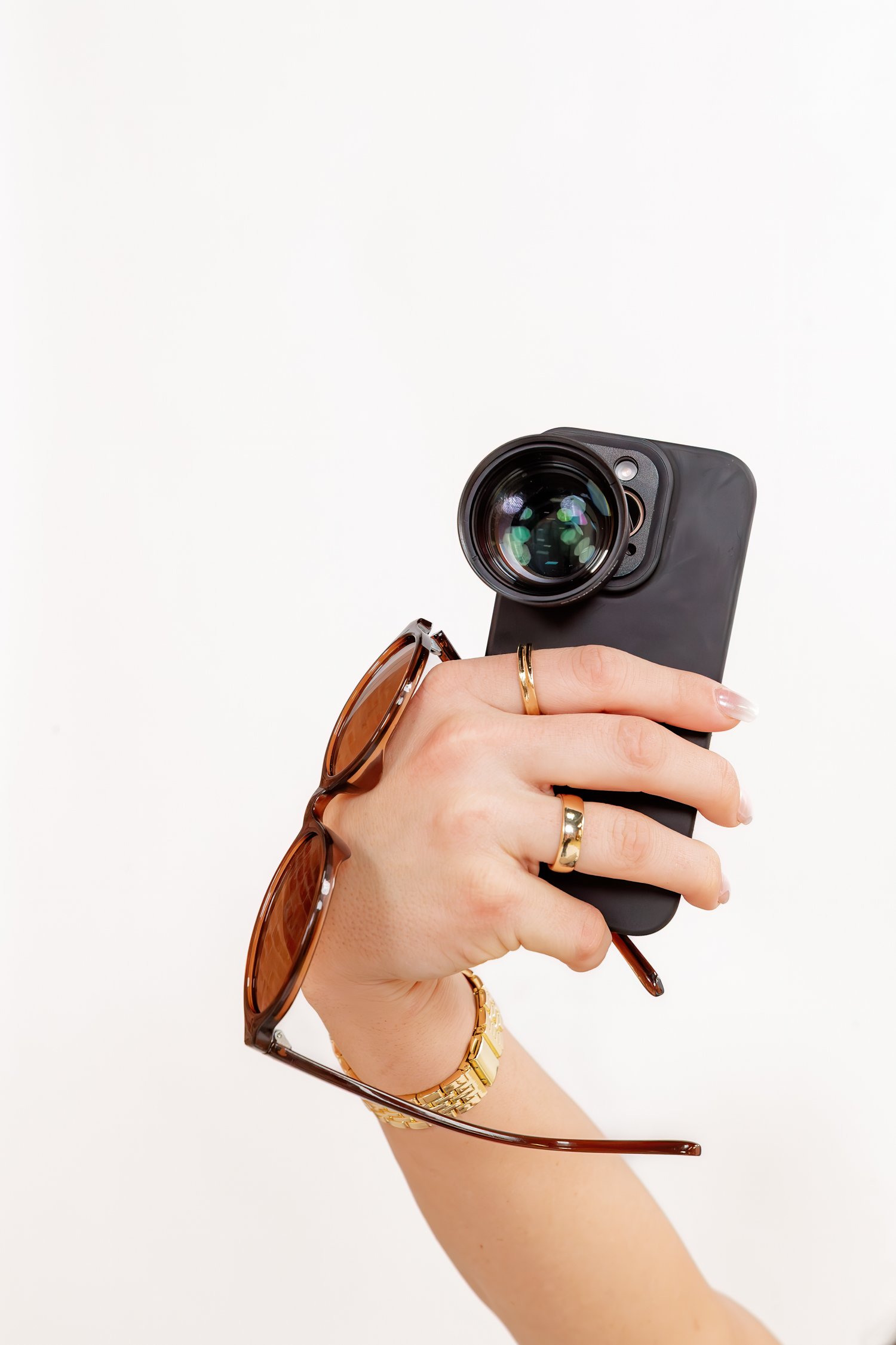 A hand holding a phone with a lens attached. Sandmarc product photography.