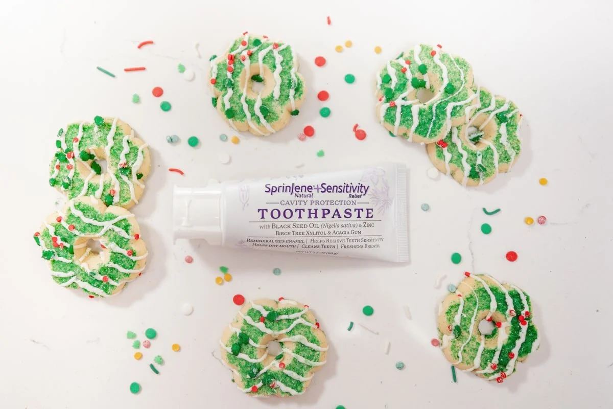 SprinJene toothpaste surrounded by green wreath cookies and red-and-green sprinkles.