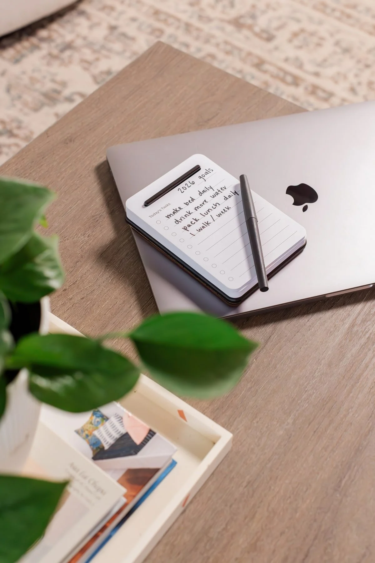 An Unstoppable Tasks notepad with 2026 goals and a pen rests on a closed laptop.