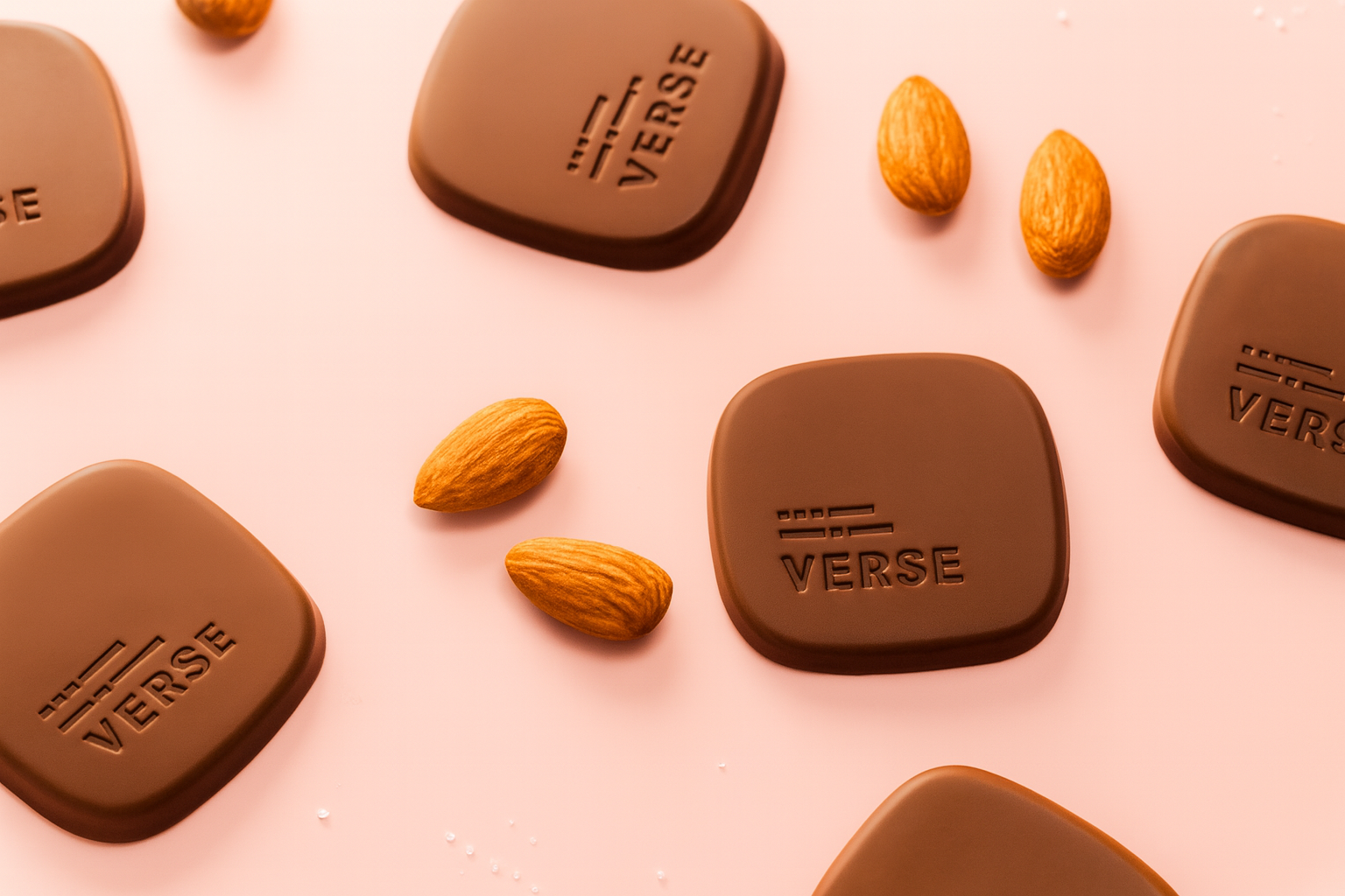 Verse chocolate product photograph with almonds on a pink background.