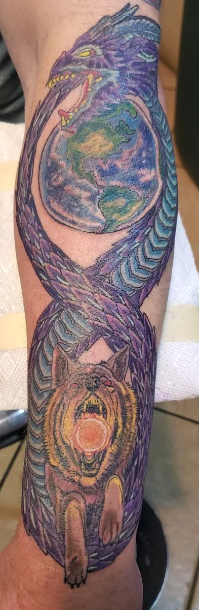Tattoo of a dragon intertwined with the Earth, with a snarling wolf at the bottom.