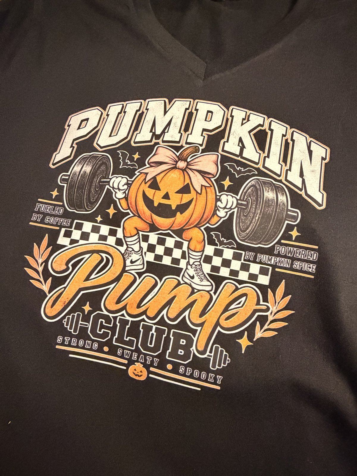 Black v-neck shirt printed with a Pumpkin Pump Club design of a pumpkin lifting weights