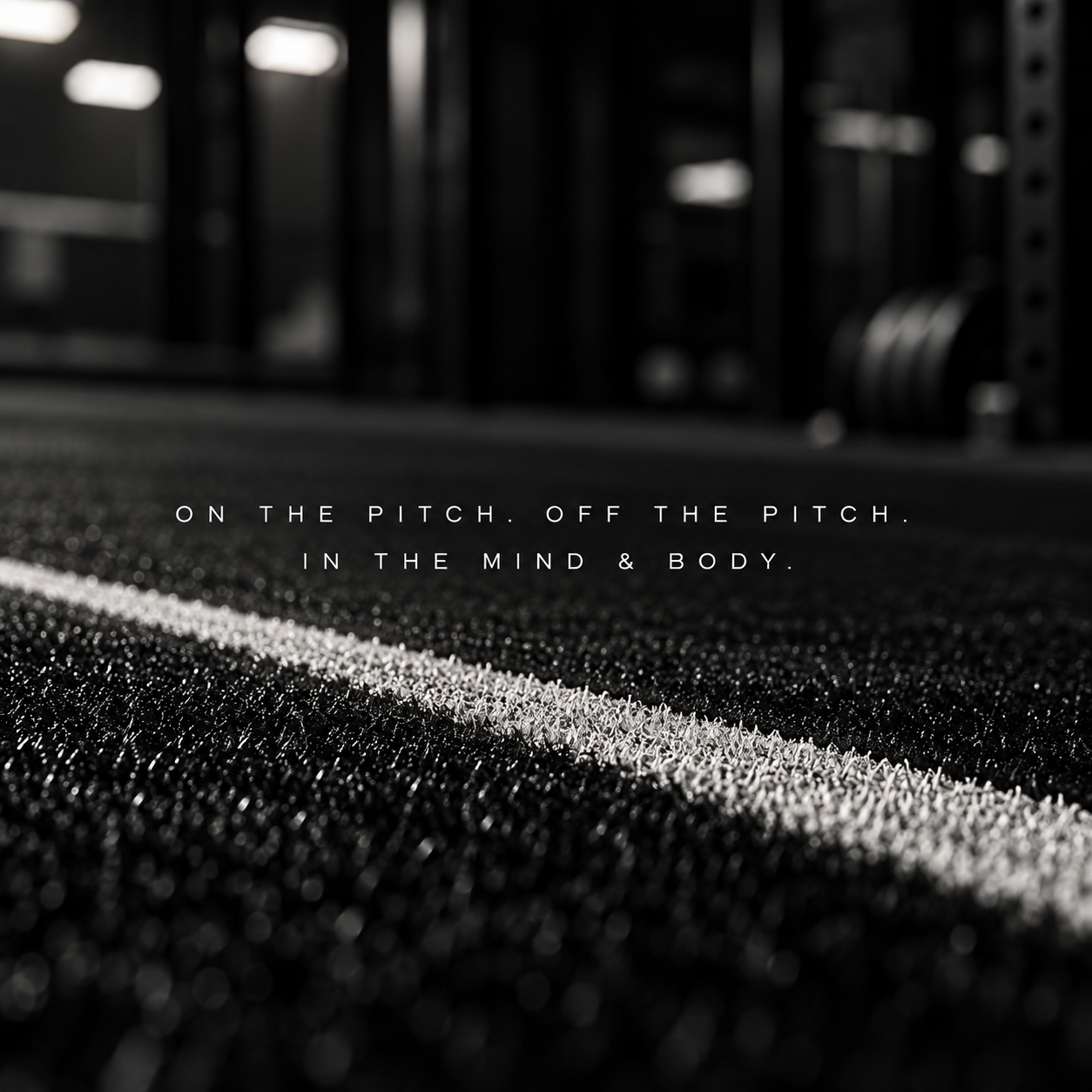 Close-up of a textured gym floor with a white line, blurred gym equipment in the background, and motivational text that reads 'On the pitch. Off the pitch. In the mind & body.'