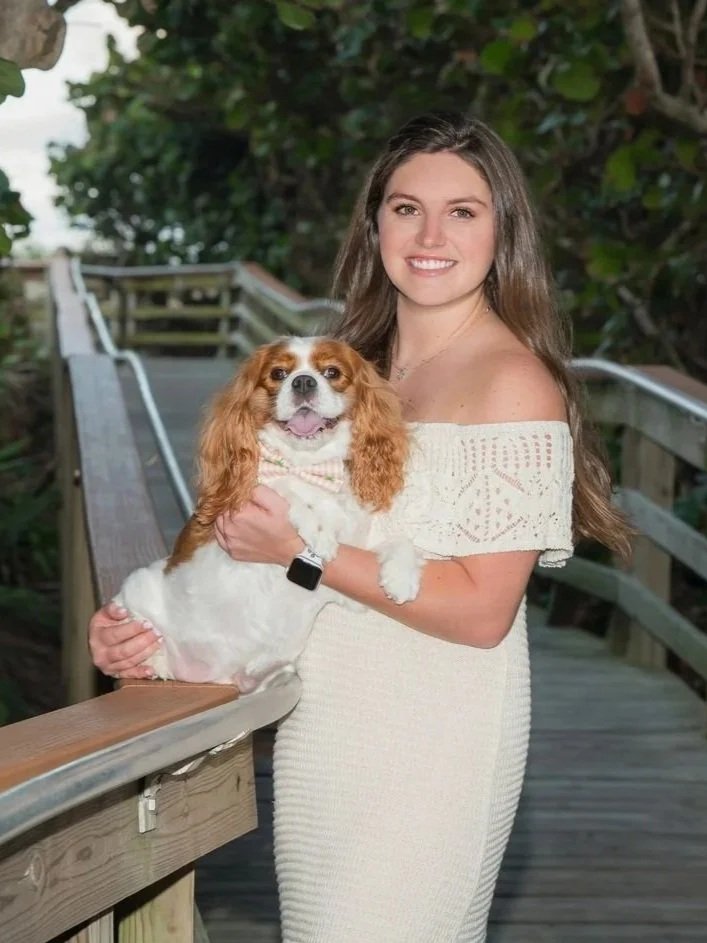 Young woman holding her Cavalier King Charles spaniel on a beach boardwalk, outdoor pet portrait Jupiter area
