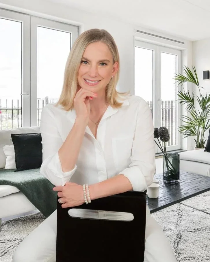 Personal branding portrait of a businesswoman in white seated in a modern waterfront living room, luxury lifestyle branding