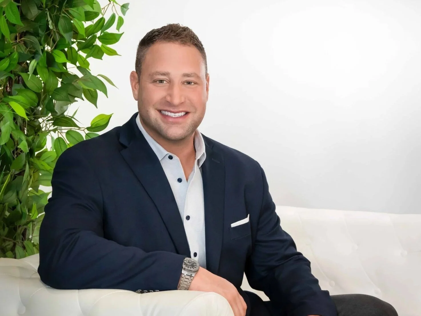 Corporate headshot of a smiling businessman in a navy blazer in a modern studio setting, Palm Beach Gardens headshot photographer
