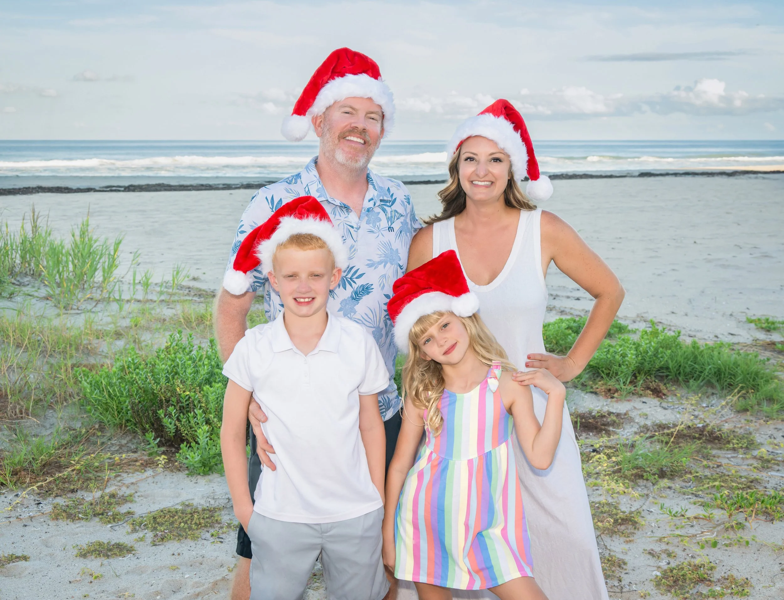 Family Christmas portrait in Santa hats on a South Florida beach by Vasi Studio, Palm Beach Gardens holiday photographer