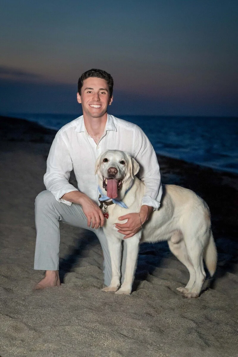 Man kneeling with his yellow Labrador on the beach at twilight, outdoor dog and owner portrait