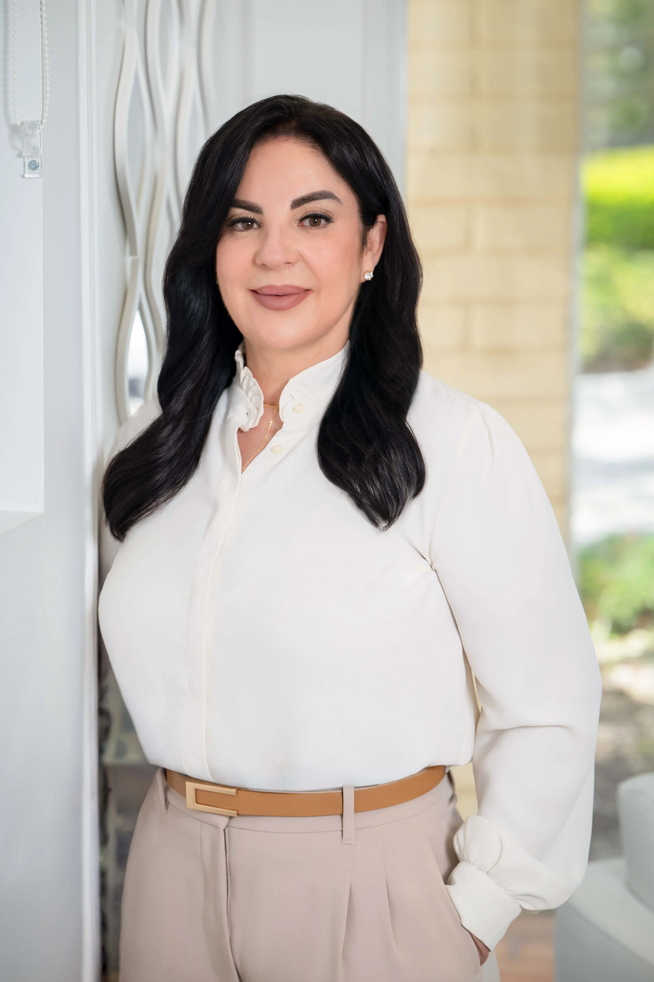Professional branding portrait of a businesswoman in a white blouse in a bright modern interior