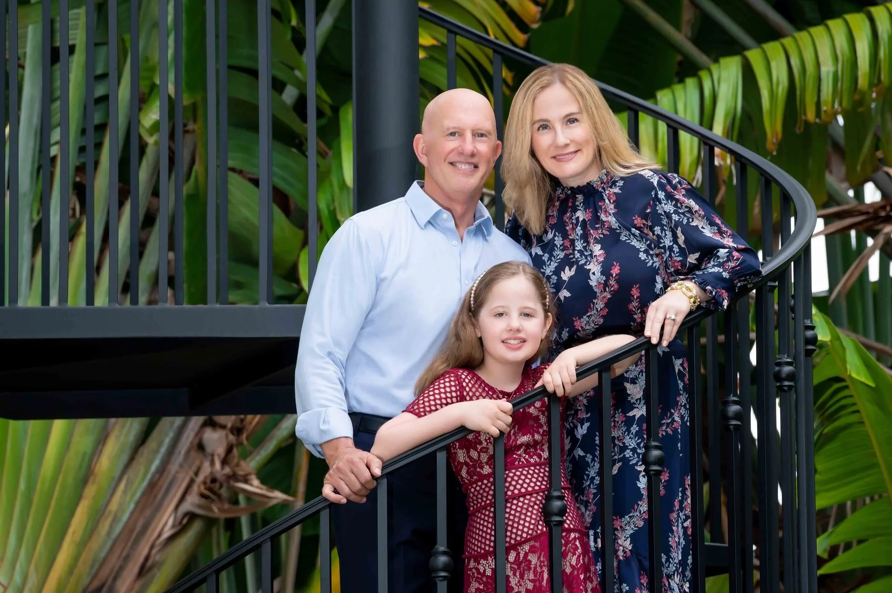 Grandparents and granddaughter on a staircase among tropical plants, multi-generation family portrait