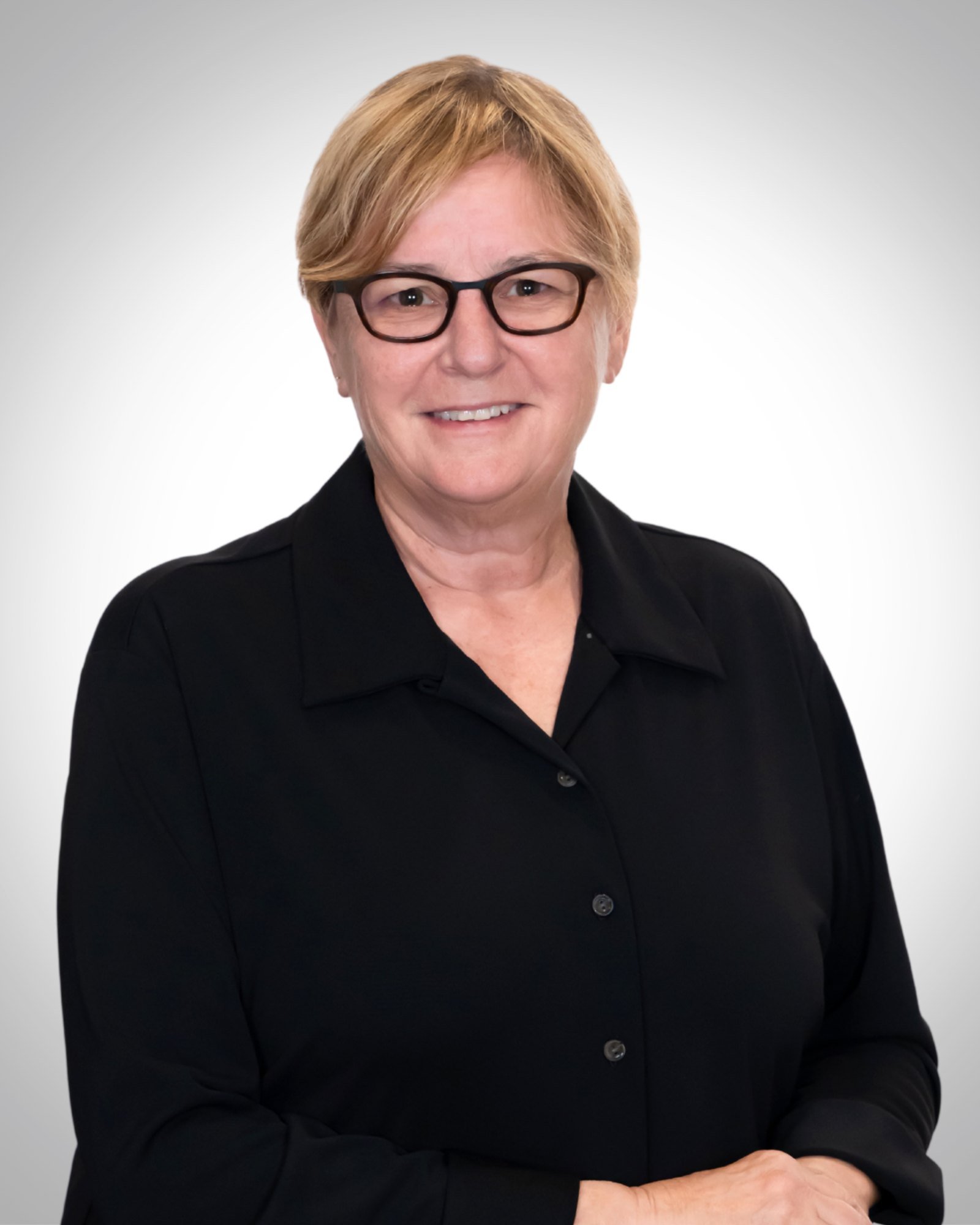 Professional headshot of a woman in glasses and a black blouse on a white background