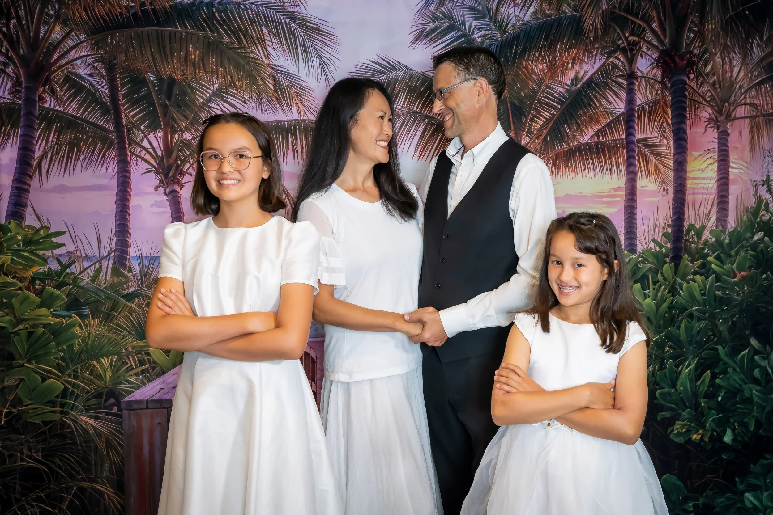 Family portrait in white with a tropical palm tree sunset backdrop in the Vasi Studio photography studio in Palm Beach Gardens, evening studio session