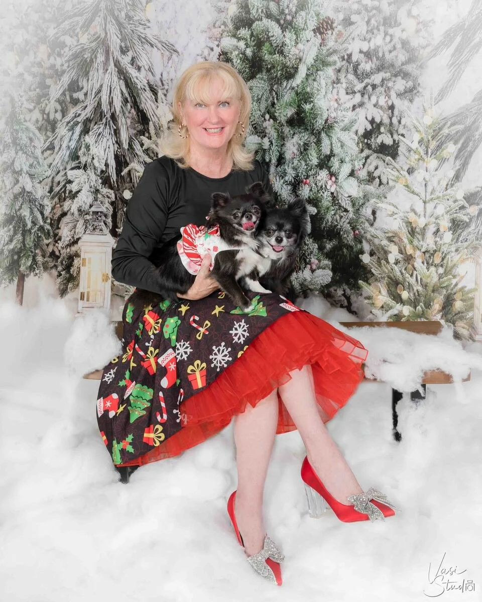 Woman in a red tulle skirt holding her small dog in a snowy winter forest set, holiday people and pet portrait