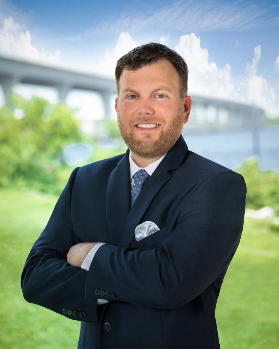 Executive portrait of a businessman in a navy suit with arms crossed outdoors near a bridge, Jupiter and Palm Beach business photography