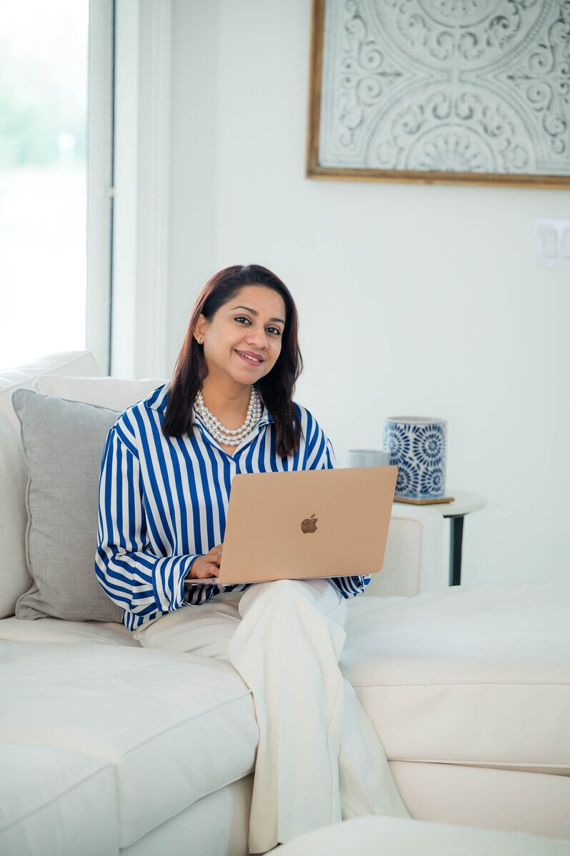 Lifestyle branding photo of a businesswoman working on a laptop on a white sofa, entrepreneur branding photography