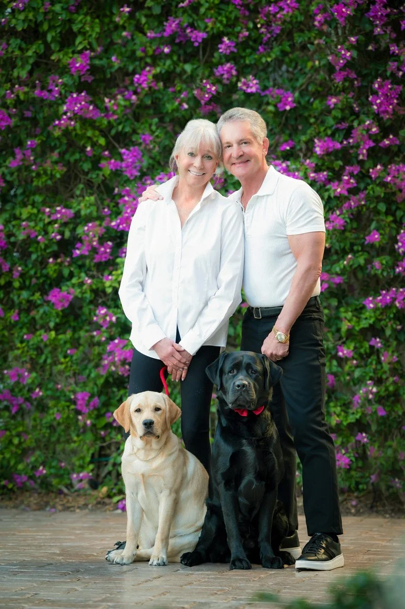 Couple with a yellow Lab and a black Lab in front of bougainvillea, family and dog portrait in South Florida
