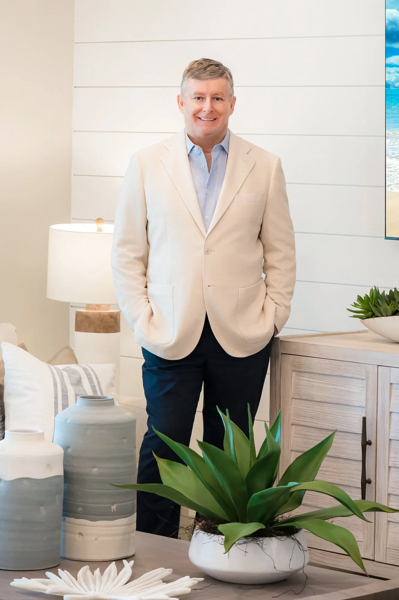 Lifestyle branding portrait of a businessman in a cream blazer in a coastal home interior, real estate branding photos