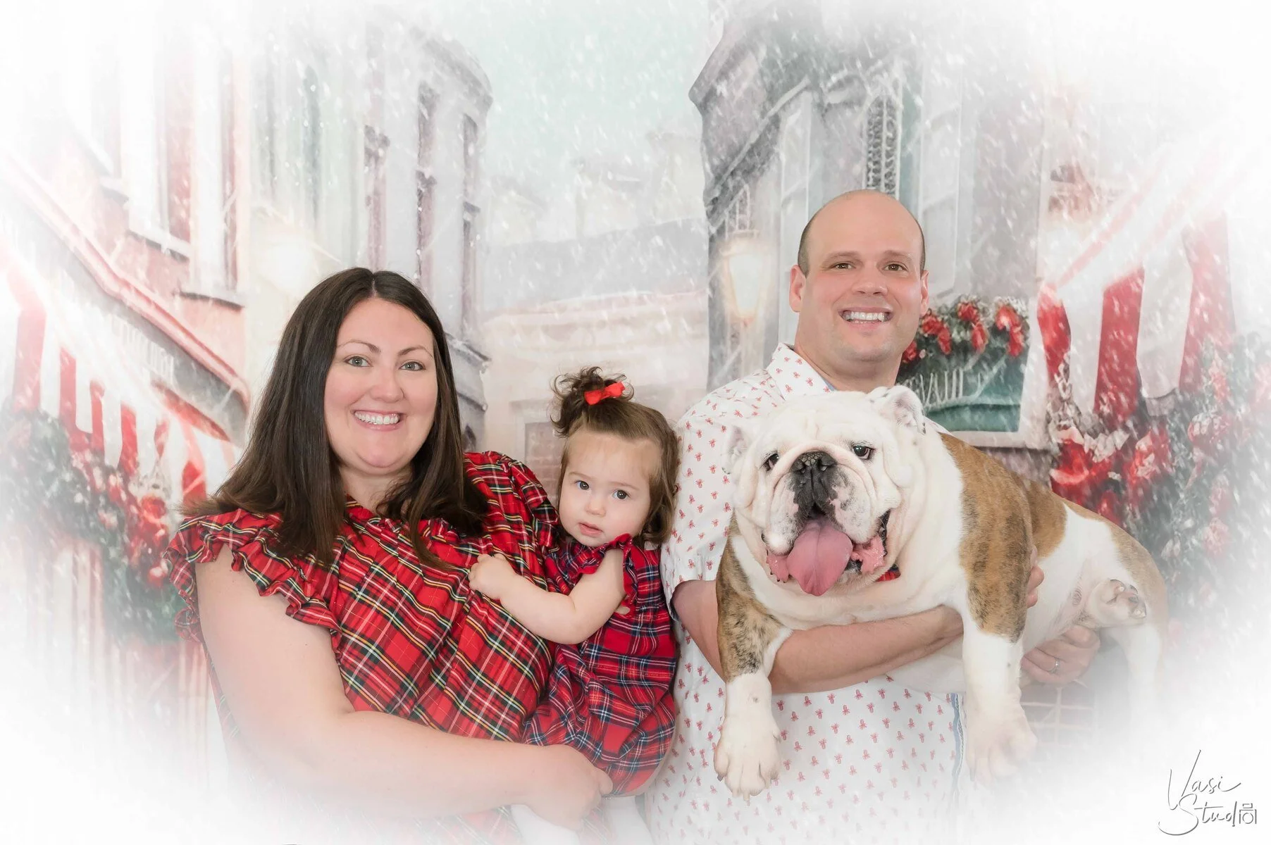 Family with a toddler and English bulldog in a candy-cane Christmas village set, holiday family and pet portrait