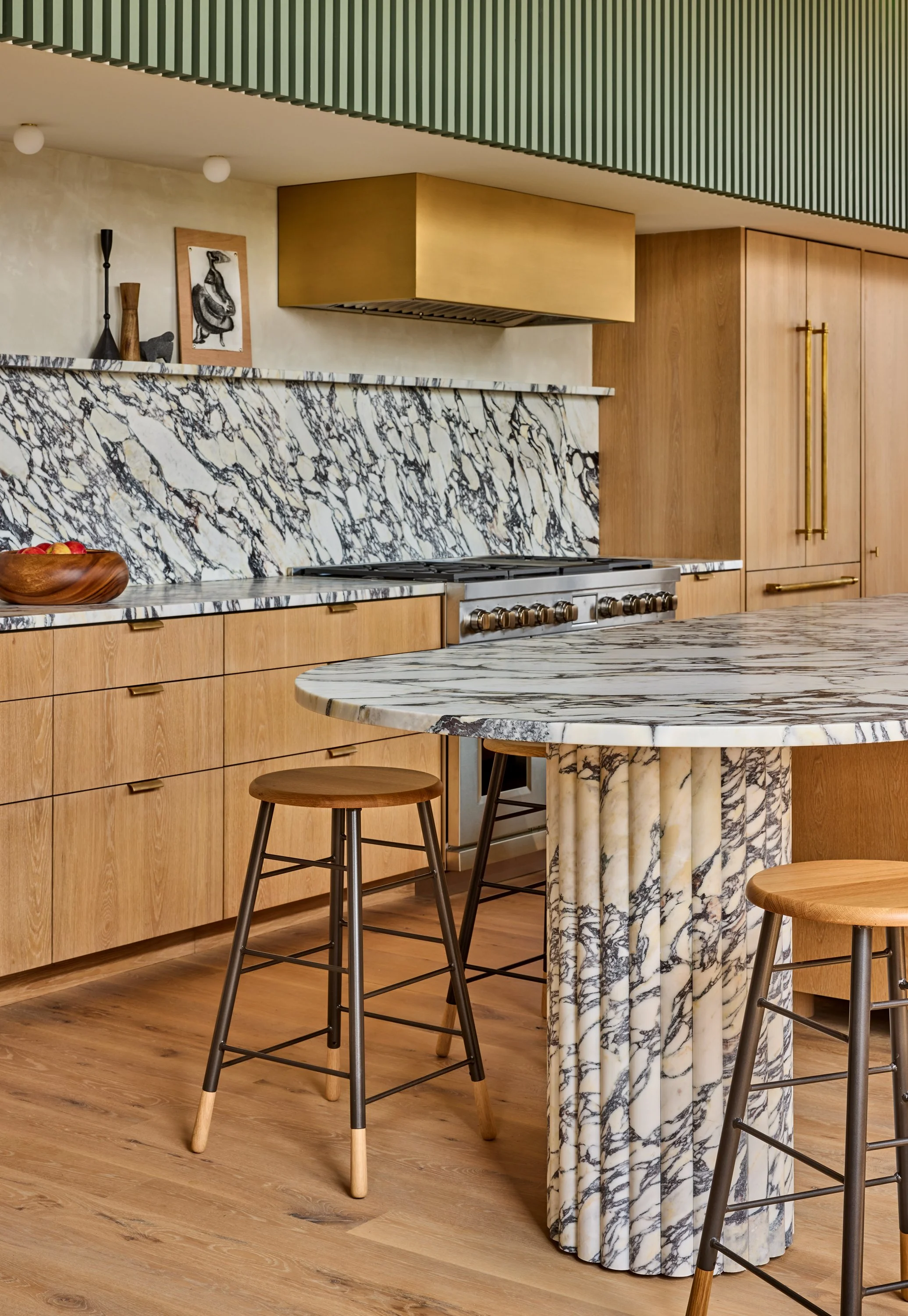 Luxury kitchen with calcutta viola marble island, white oak wooden cabinets, and black barstools.